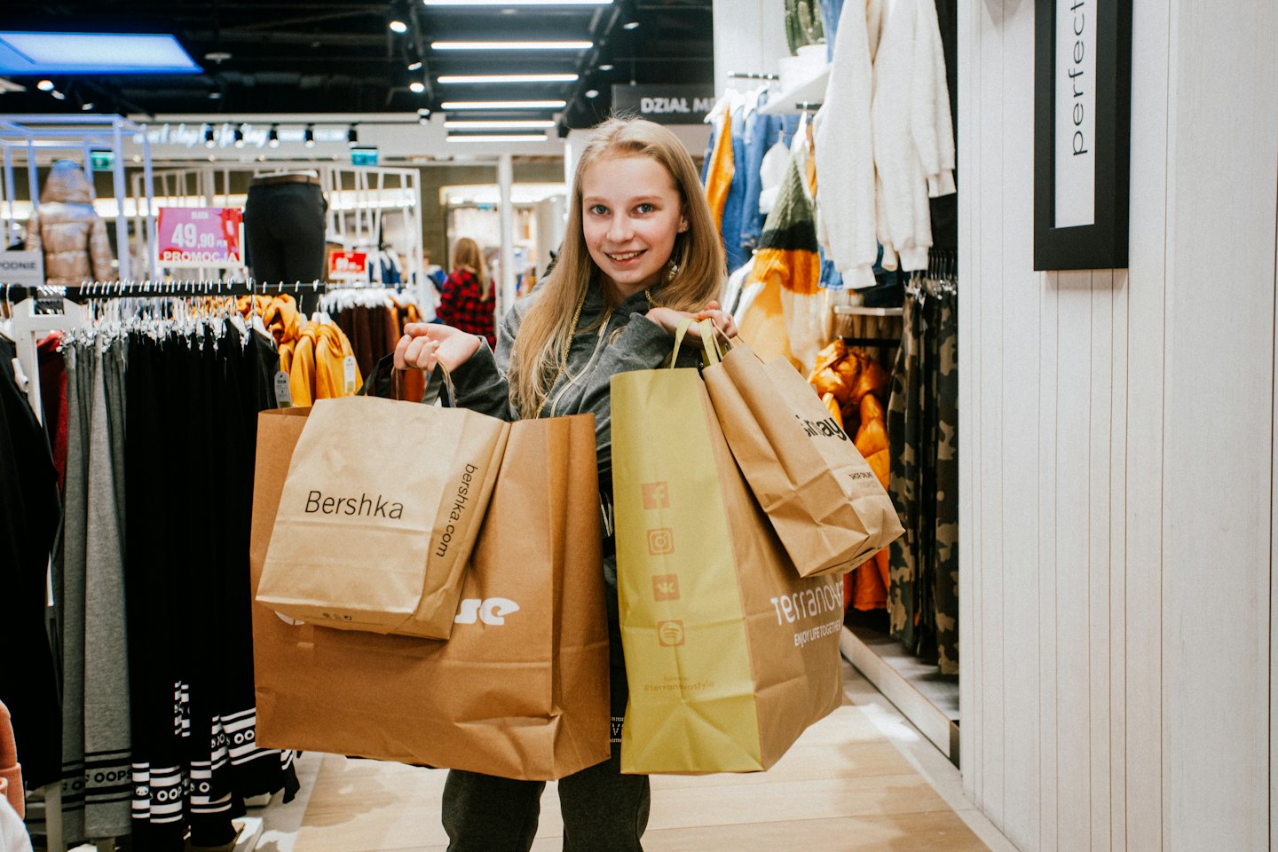 Kvinna ler och håller shoppingkassar i en klädbutik.